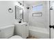 Bathroom with sleek vanity, framed mirror, and a tiled shower/tub with built-in niche, with a toilet on the left at 1940 Walker St, Las Vegas, NV 89106