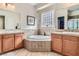 Bright bathroom featuring a soaking tub, double sinks, and wood cabinets at 2345 Gondi Castle Ave, Henderson, NV 89044