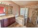 Elegant bathroom featuring a soaking tub, marble shower, and dual sink vanity with cherry wood cabinets at 3581 Rio Paloma Ct, North Las Vegas, NV 89031