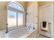 Bright bathroom featuring a tub under a large window with a door, tiled floors and textured walls at 4033 Bliss Canyon Ct, Las Vegas, NV 89129