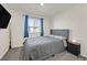Cozy bedroom with a gray upholstered bed, a TV, blue curtains, and light-colored walls at 527 Clearsable Ave, Henderson, NV 89044