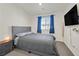 Cozy bedroom with a gray upholstered bed, a TV, blue curtains, and light-colored walls at 527 Clearsable Ave, Henderson, NV 89044