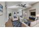 Staged living room with a ceiling fan, hardwood floors, sofa, two chairs, coffee table, and an area rug at 7973 Macklin St, Las Vegas, NV 89129