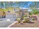 Two-story home with a three car garage, desert landscaping and a stone facade at 10001 Blairwood Ct, Las Vegas, NV 89178