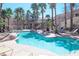 Beautiful pool area with clear blue water, lush palm trees, and comfortable lounge chairs for relaxation at 10553 Pine Pointe Ave # 201, Las Vegas, NV 89144