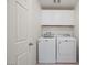 Clean laundry room equipped with modern washer, dryer, and overhead storage at 12521 Lylan Ridge St, Las Vegas, NV 89138