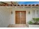 A beautifully crafted wooden front door is accented by decorative sconces and detailed facade at 208 Stonewood, Las Vegas, NV 89107