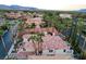 Expansive aerial view of a home with palm trees, tile roof, and lush landscaping in a residential neighborhood at 2508 Monarch Bay Dr, Las Vegas, NV 89128