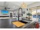 Close-up of the kitchen island featuring a sink, cutting board, and modern faucet with living area in background at 2809 Proust Ct, Henderson, NV 89044