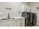 Laundry room with side-by-side gray washer and dryer, upper cabinets, white countertop, and a stainless steel sink at 2809 Proust Ct, Henderson, NV 89044