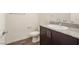 Bathroom featuring a granite countertop, dark cabinets, wood-look floors, and a toilet at 2813 Riverside Gold Ct, North Las Vegas, NV 89086
