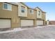 Three car garage on a paved driveway, with neutral colored townhomes and clean architectural details at 2813 Riverside Gold Ct, North Las Vegas, NV 89086