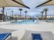 A community swimming pool and tanning deck with palm trees, shade covers, and poolside lounge chairs at 2813 Riverside Gold Ct, North Las Vegas, NV 89086