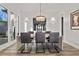 Dining room with table seating six, modern chandelier, and bright windows overlooking the courtyard at 3 Rue Allard Way, Henderson, NV 89011