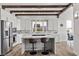 Bright kitchen features an island with counter seating, stainless steel appliances, white cabinets, and wood beam ceiling details at 3 Rue Allard Way, Henderson, NV 89011