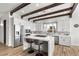 Bright kitchen features an island with counter seating, stainless steel appliances, white cabinets, and wood beam ceiling details at 3 Rue Allard Way, Henderson, NV 89011