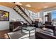 Living room with a staircase, leather furniture, glass coffee table, and unique decor at 360 E Desert Inn Rd # 1903, Las Vegas, NV 89109