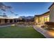 Well-manicured backyard at dusk with a beautiful landscape, brick pavers, and mountain views in the distance at 6333 Orto Vaso Ave, Las Vegas, NV 89131