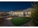 Inviting backyard featuring lush green lawn, brick pathway, and a cozy outdoor space illuminated by landscape lighting at 6333 Orto Vaso Ave, Las Vegas, NV 89131