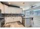 Modern kitchen with white cabinets, mosaic backsplash, stainless steel appliances, and wood-look tile flooring at 720 Camino La Paz, Henderson, NV 89012
