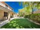 Well-maintained backyard with artificial turf, a paved patio, and lush landscaping for easy maintenance at 7427 Tomahawk Bend Ave, Las Vegas, NV 89113