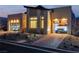 Modern home exterior featuring a two-car garage with translucent doors, modern landscaping, and a brick driveway at dusk at 10739 Agate Cliffs Ave, Las Vegas, NV 89135