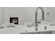 Close up of a modern kitchen island featuring a stainless steel faucet, seating and living room fireplace at 10739 Agate Cliffs Ave, Las Vegas, NV 89135