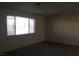 A bright living room features a window and neutral carpeting at 146 Greenbriar Townhouse Way, Las Vegas, NV 89121