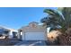 Beige single-Gathering home with a two-car garage, palm tree and low maintenance desert landscaping at 2100 Fred Brown Dr, Las Vegas, NV 89106