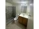 A tiled bathroom with a toilet, mirror, vanity with storage, towel rack, and tiled walk in shower at 2564 San Marcos St, Las Vegas, NV 89115