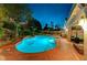Backyard oasis featuring a freeform pool, jacuzzi, and lush landscaping at twilight at 2813 Via Avanti St, Henderson, NV 89074