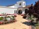 Stunning white home featuring a brick walkway, blooming flowers, and lush landscaping at 3938 E Russell Rd, Las Vegas, NV 89120