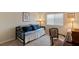 Cozy bedroom furnished with a daybed and a patterned chair, illuminated by a window with blinds at 4755 Rossini St, Pahrump, NV 89061