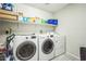 Bright laundry room features a washer and dryer, plus shelving for ample storage at 5628 Ridgeland St, North Las Vegas, NV 89031
