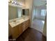 Bathroom with wood cabinets, double sinks, and a view to an adjacent bedroom at 6316 Beige Bluff St # 201, North Las Vegas, NV 89081