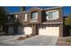 Modern townhome showcasing multi-car garage with a desert landscape and private balcony at 7290 Sheared Cliff Ln # 102, Las Vegas, NV 89149