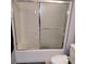 Bathroom shower and tub with sliding glass doors and white tiled walls at 7745 Fruit Dove St, North Las Vegas, NV 89084