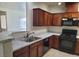 Open concept kitchen with stone countertops, stainless sink, and black appliances at 8324 W Charleston Blvd # 2033, Las Vegas, NV 89117
