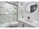 Modern bathroom features glass enclosed shower, round mirror, and updated vanity at 8469 Sewards Bluff Ave, Las Vegas, NV 89129