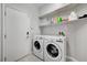 Bright laundry room with white washer and dryer units and storage shelves at 9012 Old River Ave, Las Vegas, NV 89149
