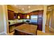 Modern kitchen featuring dark wood cabinetry, stainless steel appliances, granite countertops, and a center island at 16 Via Visione # 102, Henderson, NV 89011