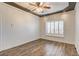 Neutral bedroom showcasing beautiful tray ceiling, ceiling fan, plantation shutters and hardwood floors at 1859 Woodhaven Dr, Henderson, NV 89074