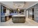 A modern kitchen features dark cabinetry, stone accent wall, and a marble countertop island with pendant lighting at 1859 Woodhaven Dr, Henderson, NV 89074
