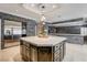 A modern kitchen features dark cabinetry, stone accent wall, stainless steel refrigerator, and a marble countertop island at 1859 Woodhaven Dr, Henderson, NV 89074