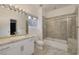 Standard-sized bathroom featuring neutral tile, a tub with sliding glass doors, and a vanity with ample storage at 2221 S Tioga Way, Las Vegas, NV 89117