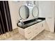 Bathroom vanity featuring a black countertop, dual round mirrors, and white cabinets at 2221 S Tioga Way, Las Vegas, NV 89117