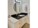 Bathroom vanity featuring a black countertop, round mirror, and white cabinets at 2221 S Tioga Way, Las Vegas, NV 89117