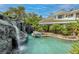 Beautiful backyard pool featuring a rock waterfall and lush tropical landscaping at 2221 S Tioga Way, Las Vegas, NV 89117