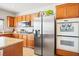 Bright kitchen featuring wood cabinets, granite countertops, stainless steel appliances, and tile flooring at 2305 Dalton Ridge Ct, North Las Vegas, NV 89031
