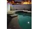 Backyard swimming pool surrounded by concrete patio at nighttime at 2720 Knightsbridge Rd, Henderson, NV 89074